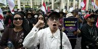 Frauen protestieren in Jakarta gegen angeblichen Wahlbetrug - eine Frau erhebt die Faust - im Hintergrund Flaggen