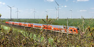 Ein Regionalexpress fährt durch eine Landschaft mit einem Windpark