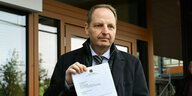 Thomas Heilmann steht mit einem DinA4 Blatt vor dem Bundesverfassungsgericht und hält sein Papier stolz in die Kamera