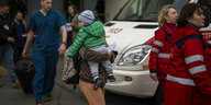 Eine Frau mit einem Kind auf dem Arm verlässt eine Kinderklinik in der Ukraine