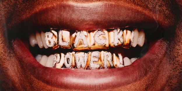 Foto von einem geöffneten Mund, die Zähne sind mit Gold und Edelsteinen besetzt