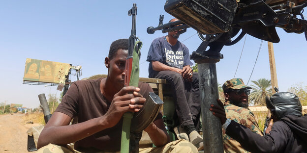 Ein Soldat der sudanesischen Armee sitz auf einem Pick-up und hält sein Gewehr fest